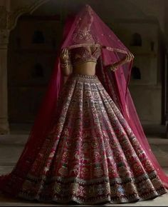 a woman in a pink and gold bridal outfit standing with her hands on her hips