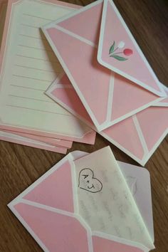 some pink envelopes with writing on them and one has a heart drawn on it