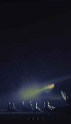 a group of people sitting on top of a bench under a rain covered sky at night