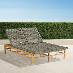 a lounge chair sitting on top of a cement floor next to a green hedge covered wall