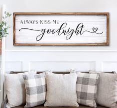 a wooden sign that says, always kiss me goodnight on the wall above a couch