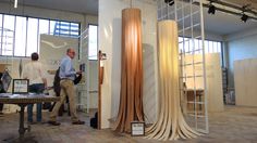 two men standing next to each other in front of tall wooden sculptures on display at an art show