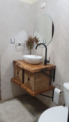 a white sink sitting on top of a wooden shelf next to a mirror and toilet