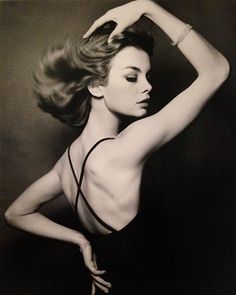 a black and white photo of a woman with her hands on her head, wearing a bathing suit