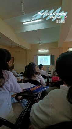 a group of people sitting at desks in front of a projector screen with the words practical classes on it