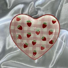 a heart shaped plate with strawberries on it sitting on a tablecloth covered surface