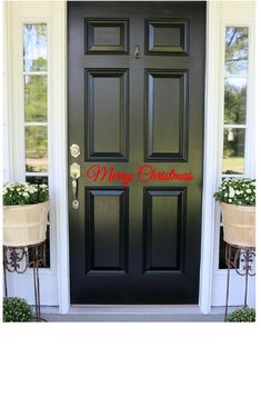 a black door with merry christmas written on it and two planters next to it