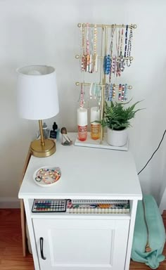 a white table with jewelry on it and a lamp in the corner next to it