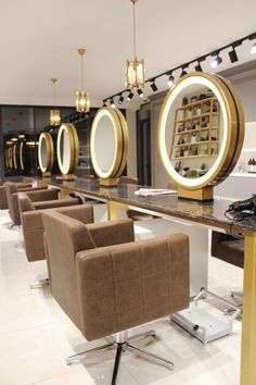 a salon with chairs, mirrors and lights on the wall above it's counter