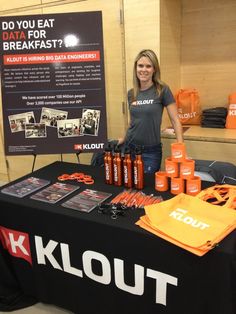 a woman standing next to a table with orange items on it and a sign that says klout do you eat data for breakfast?