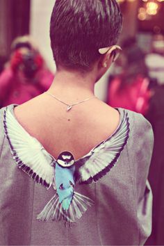 the back of a woman's neck with a blue and white bird on it