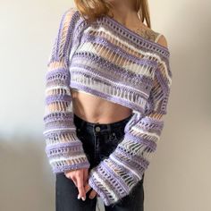 a woman wearing a purple and white striped top with sheer sleeves, standing in front of a wall