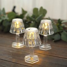 three clear glass lamps sitting on top of a wooden table