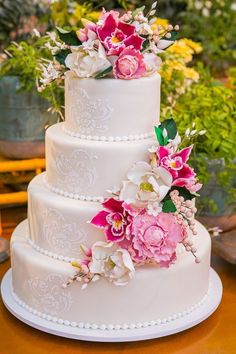 a three tiered white wedding cake with pink flowers