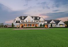 a large white house sitting on top of a lush green field