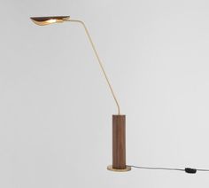 a floor lamp with a wooden base and a light bulb on the end that is plugged in