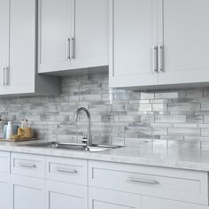 a kitchen with white cabinets and marble counter tops