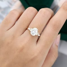 a woman's hand with a diamond ring on top of her finger and the other hand holding an engagement ring