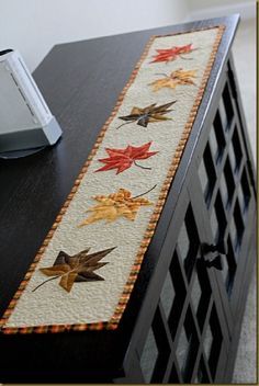 a table runner with leaves on it sitting next to a computer keyboard and mouse pad