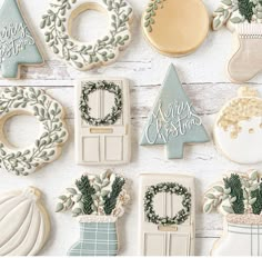 decorated christmas cookies are arranged on a white table with wreaths, stockings and stocking