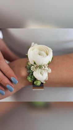 a woman's arm with a white flower and greenery on it, while wearing a ring