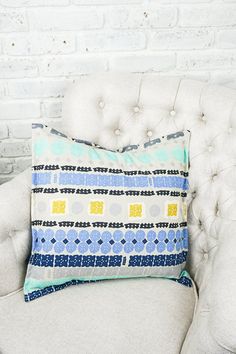 a white chair with a blue and yellow pillow sitting on it's backrest