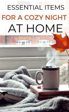 an open book and cup on a window sill with the words essential items for a cozy night at home