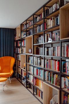 an orange chair sitting in front of a bookshelf filled with lots of books