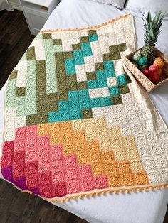 a pineapple sits on top of a bed next to a crocheted blanket