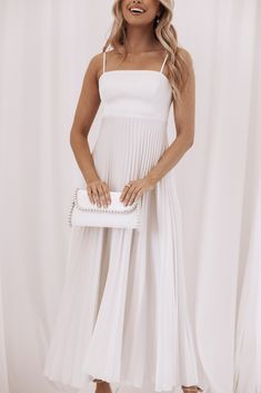 a woman wearing a white dress and holding a white purse in front of a white background