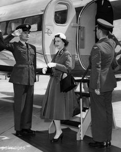 a black and white photo of two people in uniform standing next to an air plane