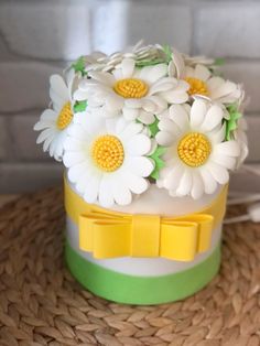 a hat with flowers on it sitting on top of a straw hat box next to a brick wall