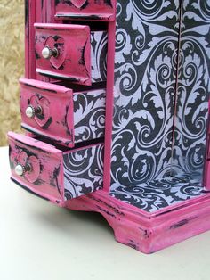 a pink and black dresser sitting on top of a table