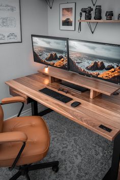 two computer monitors sitting on top of a wooden desk next to a brown leather chair