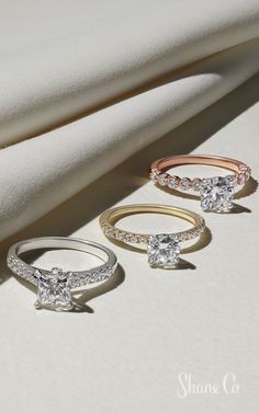 three different types of engagement rings sitting on top of a white cloth next to each other