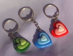 three heart shaped key chains on a white surface