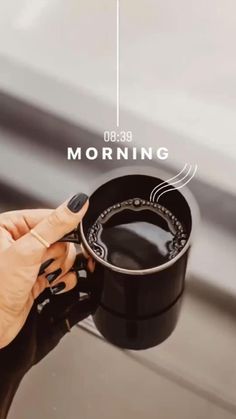 a woman holding a cup of coffee with the words morning written on it in front of her