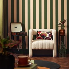 a living room with striped wallpaper and a white chair in the corner next to a table