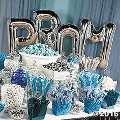 a table topped with lots of blue and white candy bar items next to balloons that spell out the word mom