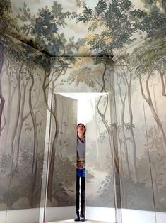 a man is standing in front of a mural with trees on the ceiling and walls