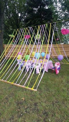 an outdoor party with balloons and streamers in the shape of a tent on grass