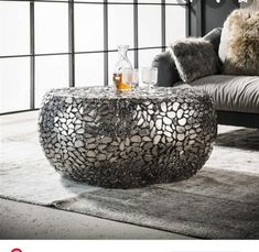 a glass table sitting on top of a rug in front of a couch with pillows