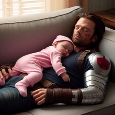 a man laying on top of a couch next to a baby in a pink shirt