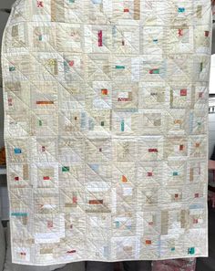 a person holding up a large white quilt