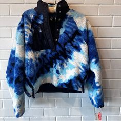 a blue and white tie - dyed jacket hanging on a brick wall next to a black button up shirt