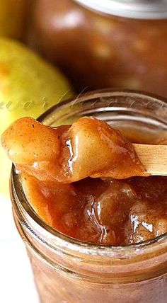 a jar filled with apple jam next to an apple