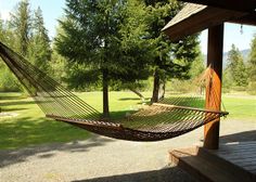 a hammock hanging from the side of a wooden structure next to a picnic table