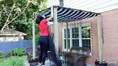 a woman in red shirt and black leggings working on an outdoor awning