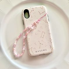 a cell phone with a pink beaded lanyard attached to it on a white plate