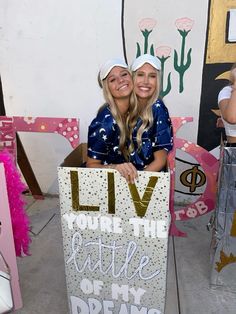 two women holding up a sign that says live you're the little one dreams